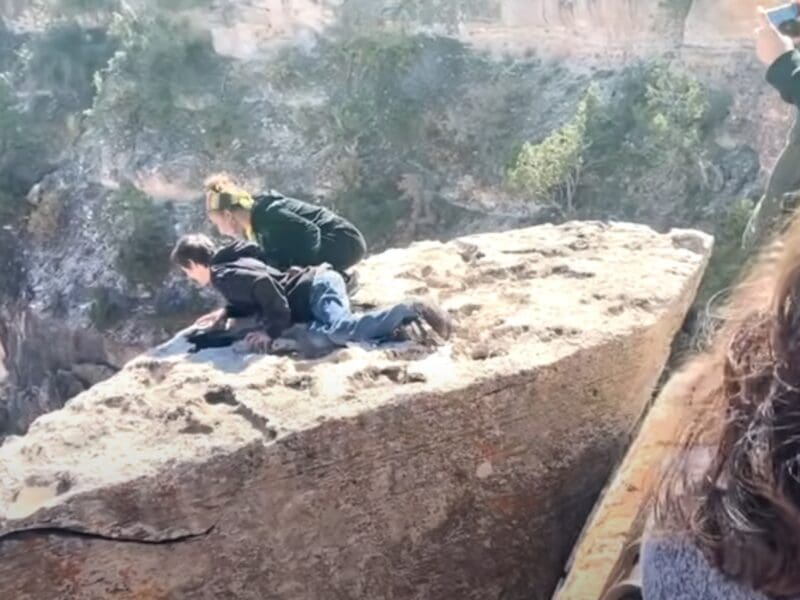 Tourists hop protective railing at Grand Canyon National Park.